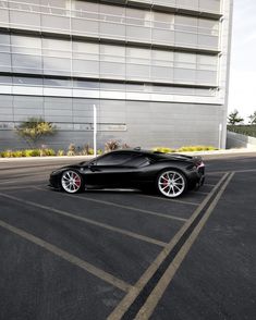 a black sports car is parked in the parking lot near a tall building with windows