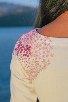 the back of a woman's white shirt with pink flowers on it