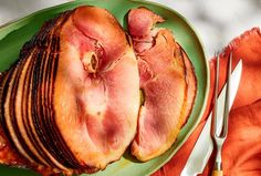 two pieces of bacon on a green plate with utensils and napkins next to it