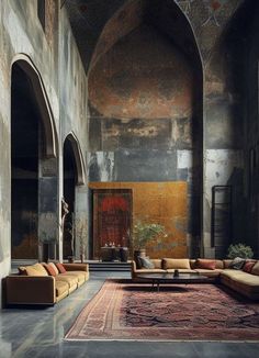 a living room with couches and rugs on the floor in front of an archway