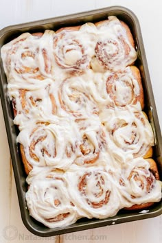 a pan filled with cinnamon rolls covered in icing