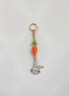 a keychain with a rabbit holding a carrot on it's back,