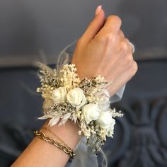 a woman's arm wearing a bracelet with flowers and leaves on it, while holding her hand in the air