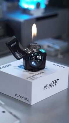 a watch sitting on top of a box with a lighter in it's mouth