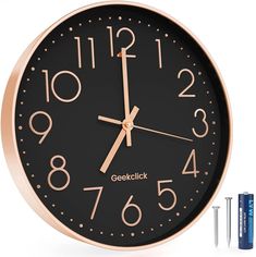 a black and gold clock with two batteries next to it