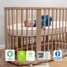 a baby laying in a wooden crib with stickers on it's sides