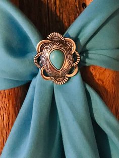 Wild Rag Western concho slide. This one is Aztec  pattern with silver in scalloped shape with pear shaped turquoise stone at center. lThis is a simple slide and will go with all your scarves.  This is smaller Slide measuring  1-1/4 and 1.5" across. Has custom backing to hold scarf made of silver solder and stainless. Please check out our other items as some are complimentary to this item. If you buy 2 or more items you will get 15% off! Spend $50 and get 20% off. We can ship multiple items for one normal shipping cost. We take custom order requests as well. Western Scarf, Scarf Slide, Floral Bandana, Wild Rag, Southwestern Design, Cowboy Cowgirl, Aztec Pattern, Cowboy And Cowgirl, Turquoise Stone