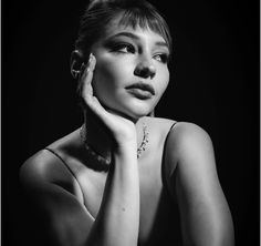 a black and white photo of a woman with her hand on her chin looking at the camera