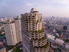 an aerial view of a building with trees growing on the top and other buildings in the background