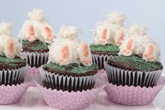 four cupcakes with white frosting and pink flowers are on a cake plate