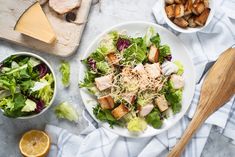 a salad with chicken, lettuce and parmesan cheese is on the table