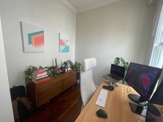 a desk with a computer, keyboard and monitor on it in front of a window