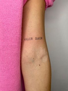 a woman's arm with the words killer queen written on it, in black ink