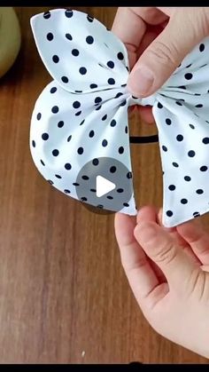 someone is holding up a bow made out of paper and fabric with black polka dots on it