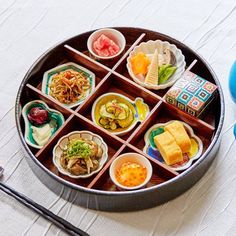 a bento box filled with different types of food and chopsticks on a table