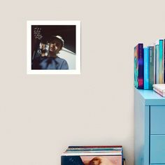 a blue dresser with books, magazines and a poster on the wall next to it