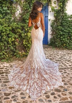 a woman in a wedding dress standing on a cobblestone walkway looking back at the camera