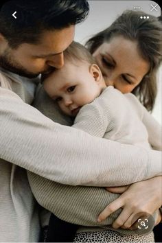 a man and woman holding a baby in their arms