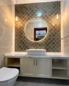 a white sink sitting under a mirror in a bathroom next to a wall mounted toilet