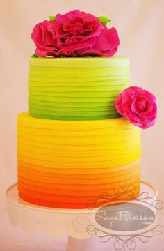 there is a multi - colored cake with flowers on top and the bottom tiers are stacked high