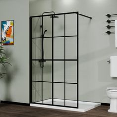 a white toilet sitting next to a shower in a bathroom on top of a hard wood floor