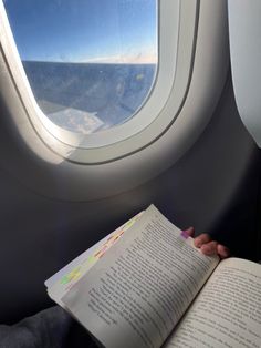 someone is reading a book on an airplane