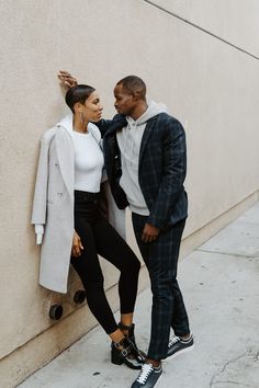 a man and woman leaning against a wall