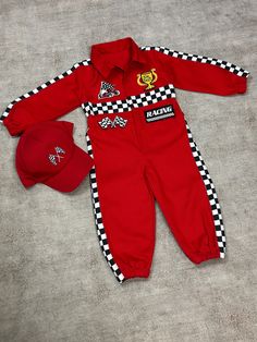 a baby's red racing suit and hat are laying on the floor