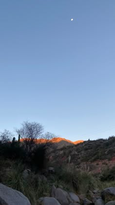 the moon shines brightly in the sky above some rocks