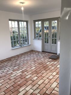 an empty room with brick floors and double doors