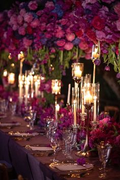 a long table with candles and flowers in the center is set for an elegant dinner