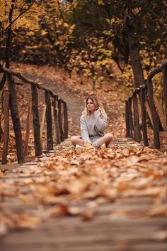 a woman sitting on a bridge surrounded by leaves