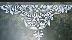 an intricately designed wall hanging on the side of a concrete floor with white paint