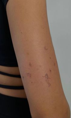 a woman's arm with small stars and zodiac signs on the back of it