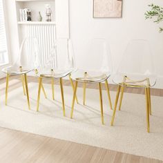 three clear chairs sitting on top of a wooden floor next to a white book shelf