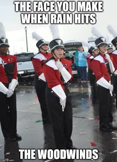 a group of people that are standing in the rain with some marching equipment on their heads