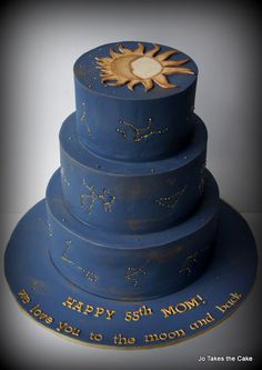 a three tiered blue cake with gold stars and the words happy 50th mom on it