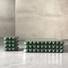 two green boxes sitting next to each other on top of a cement floor in front of a wall