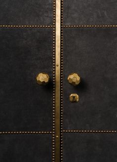 two golden knobs on the side of a blue door with studded edges and gold trim