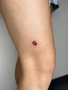 a ladybug tattoo on the back of a woman's thigh is shown