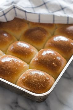 a baking pan filled with rolls on top of a marble counter