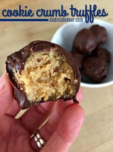 a hand holding a half eaten cookie crumb truffles in front of a bowl