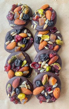 chocolate covered donuts topped with nuts and dried fruit on top of a countertop