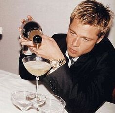 a man is holding a wine glass in front of his face while sitting at a table