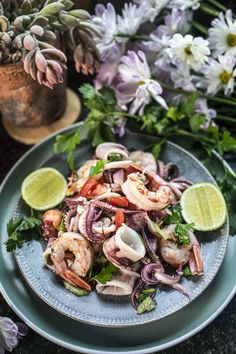 an octopus salad on a plate with limes and flowers