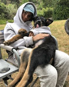 a person sitting in a chair with two dogs on their lap and one is holding the dog