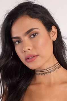 a woman with long hair wearing a choker necklace and matching earrings, looking at the camera