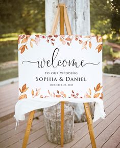 a welcome sign is on an easel for the guests to take in their wedding ceremony