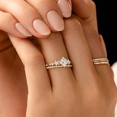 a woman's hand with three rings on her fingers and one ring in the middle