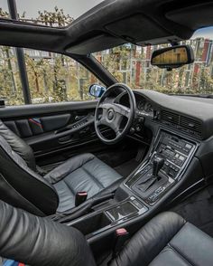 the interior of a sports car with black leather seats and steering wheel, in front of a cityscape